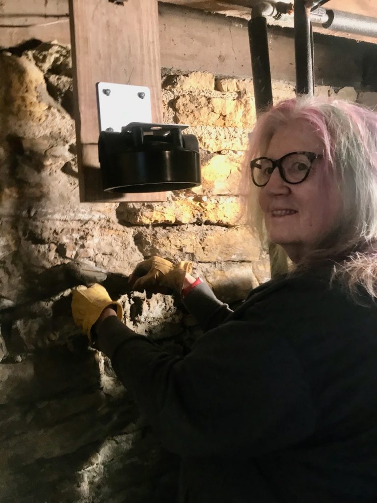 Deborah tuck-points the basement wall that has eroded its mortar over a century.