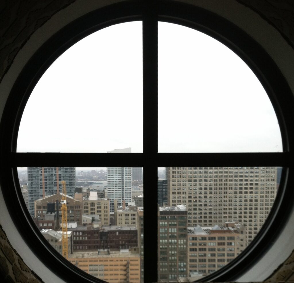Looking out a circular window at the Chicago skyline.
